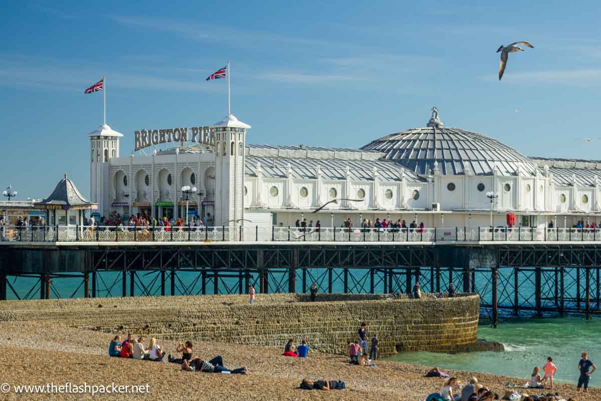 people relaxing on brighton beach with pier in background