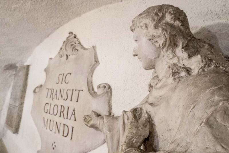 stone sculpture of an angel and a plaque with a latin inscription at the capuchin crypt in brno