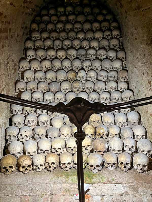 modern sculpture in front of a stack of human skulls