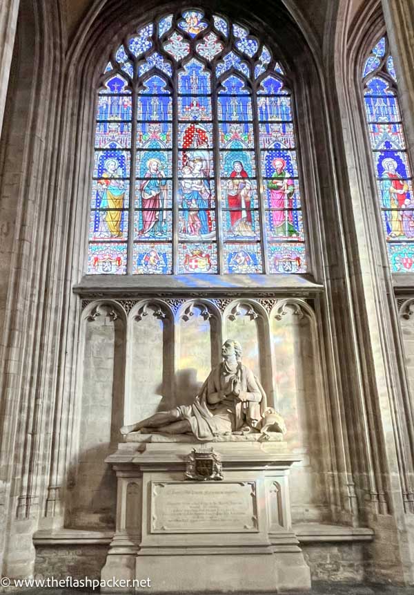 carved stone monument in front of vibrant stained glass window