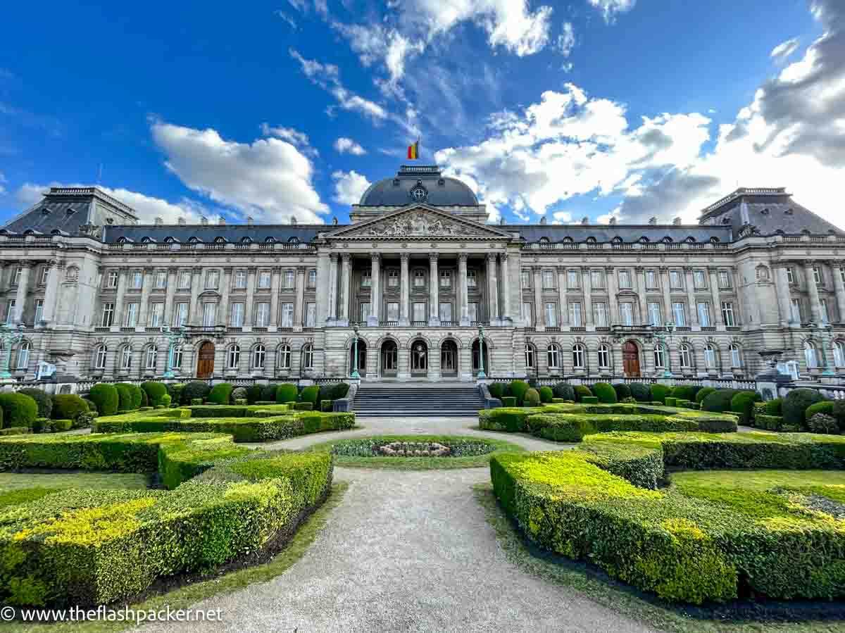 vast facade of palace building fronted by small landscaped garden