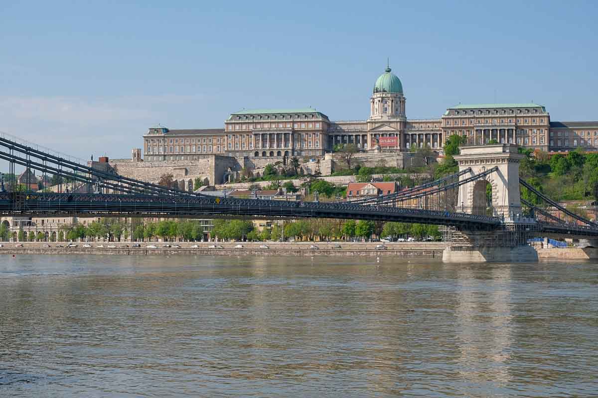 budapests chain bridge across the river danube with large palace in backgriubd