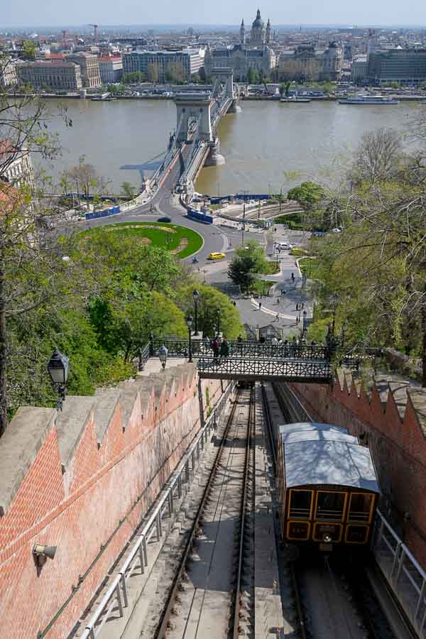 a funicular train in budapest with the river and chain bridge in background