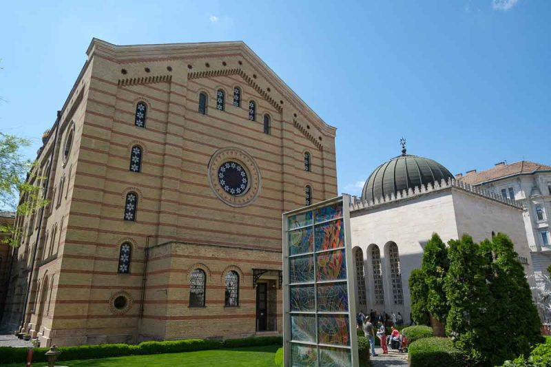 courtyard at budapest dohany street synagogue with exterior walls of 2 buildings and an installation of panes of coloured glass