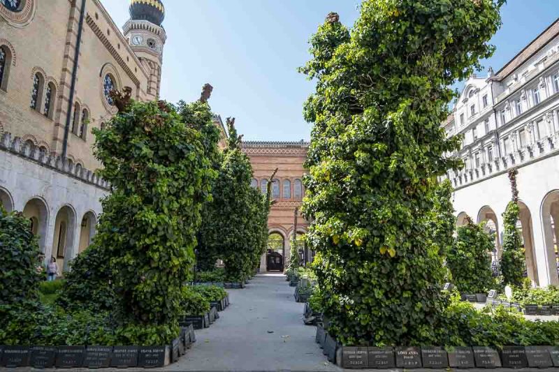 courtyard with low grey gravestones and trees at great synagogue of budapest hungary