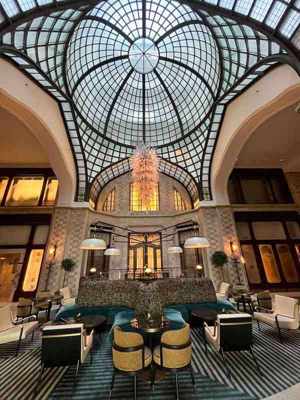 art nouveau lobby of gresham palace in budapest with domed skylight and chairs and sofas