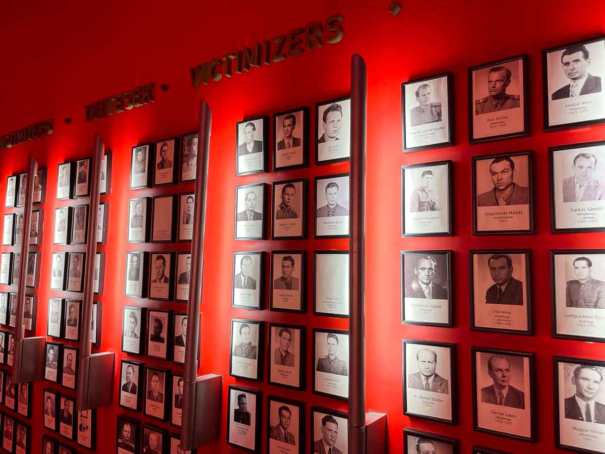 a wall of photographs of the victims of oppression mounted on a red wall