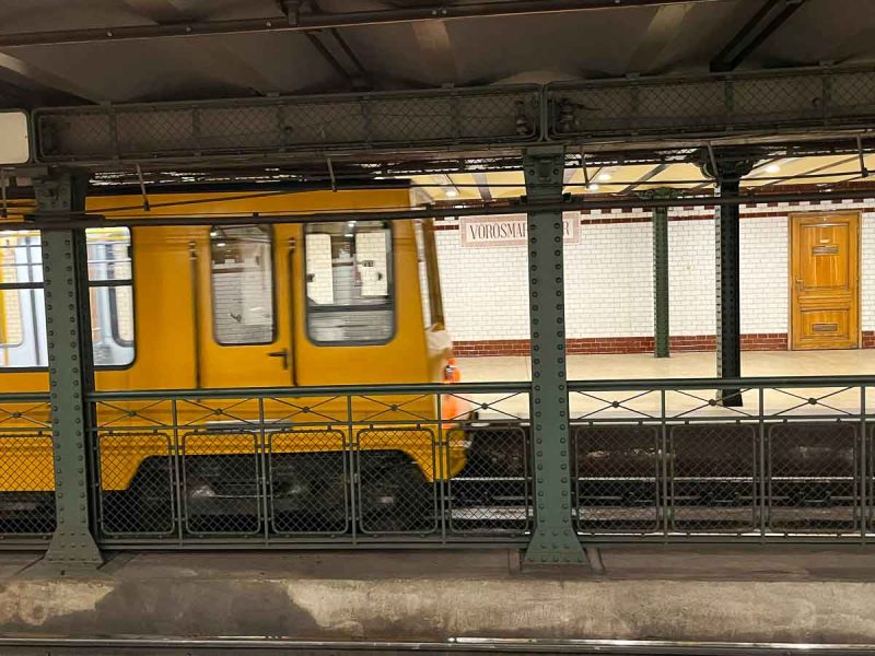 yellow metro train pulling into a platform in budapest