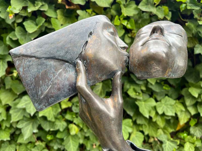 modern bronze sculpture of a person kissing the cheek of another person