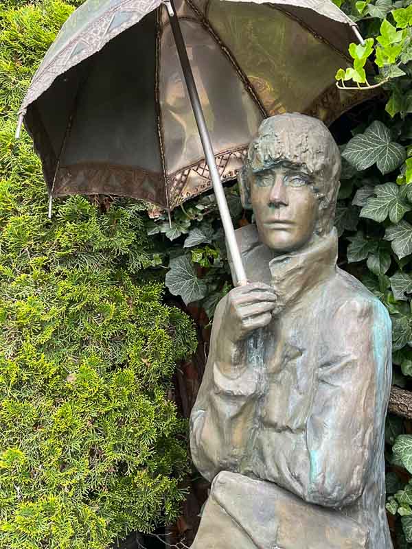 modern bronze sculpture of a woman sheltering under an umbrella