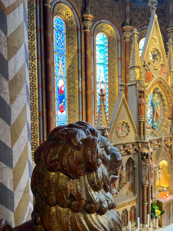 sculpture of a lion's head overlooking a gilded altar in a church