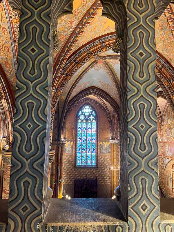 rectangular columns with swirly patterns in front of brightly painted arches inside matthias church buda