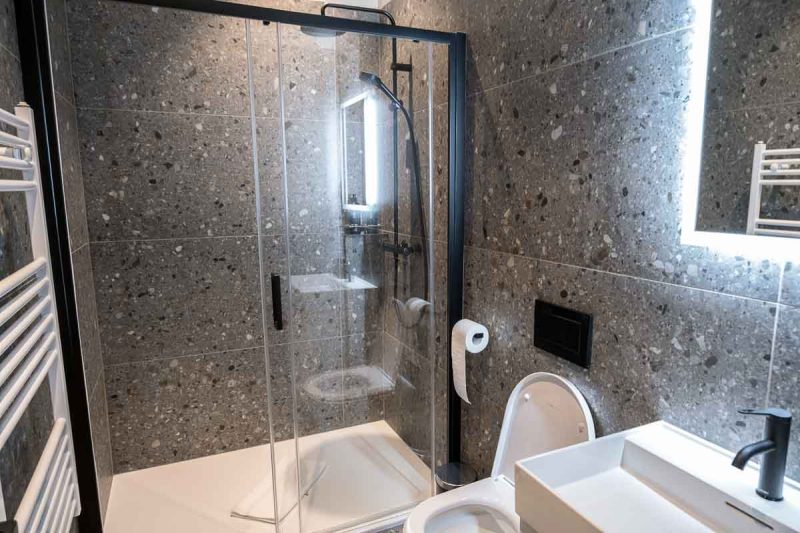 bathroom of hotel room with large shower toilet and white basin