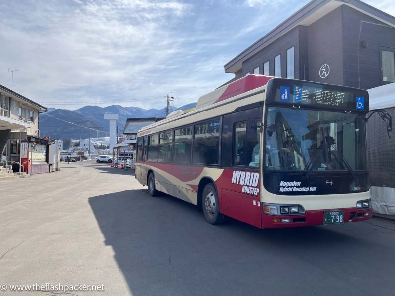 red and cream bus waiting outside railway station