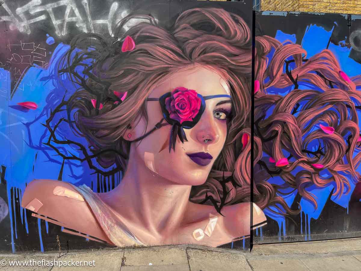 large wall mural of a woman wearing a rose as an eye patch