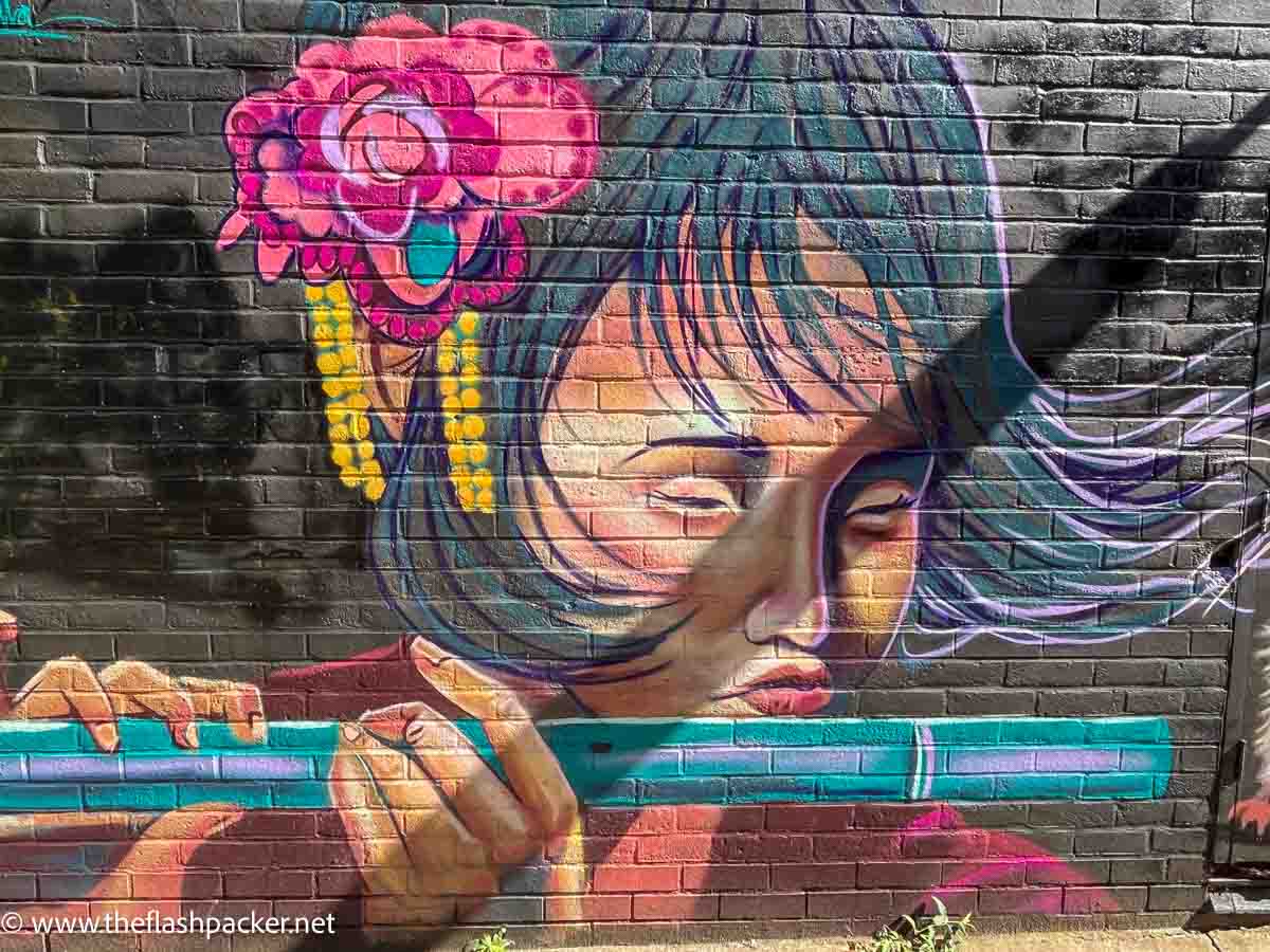 street art in camden of an asian girl playing a flute