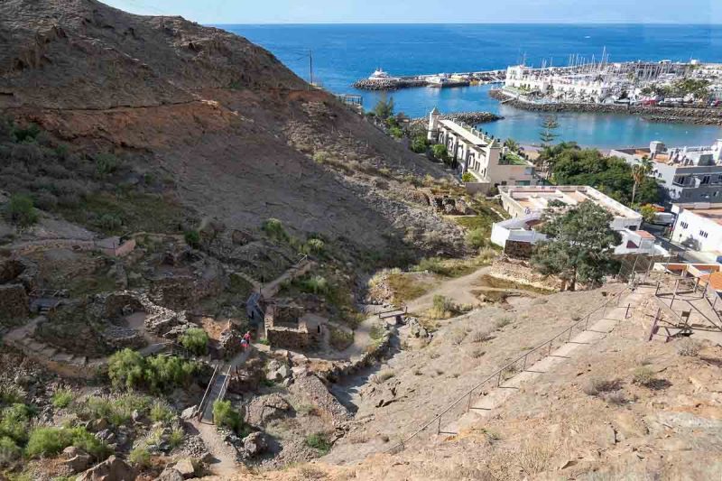 birds eye view of a small archaeological site with sea and marina in the background