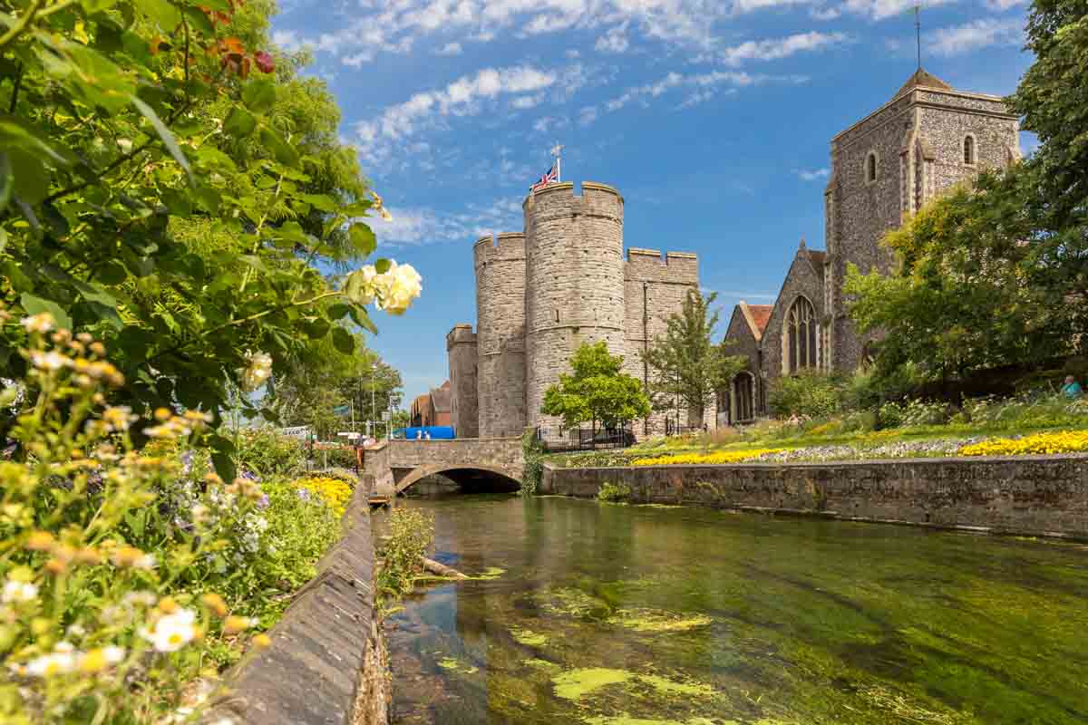 old stone buildings and 2 towers by side of river