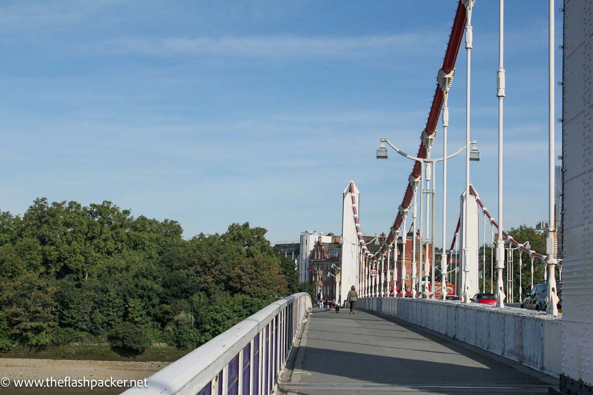 woman and dog walking across bridge in london