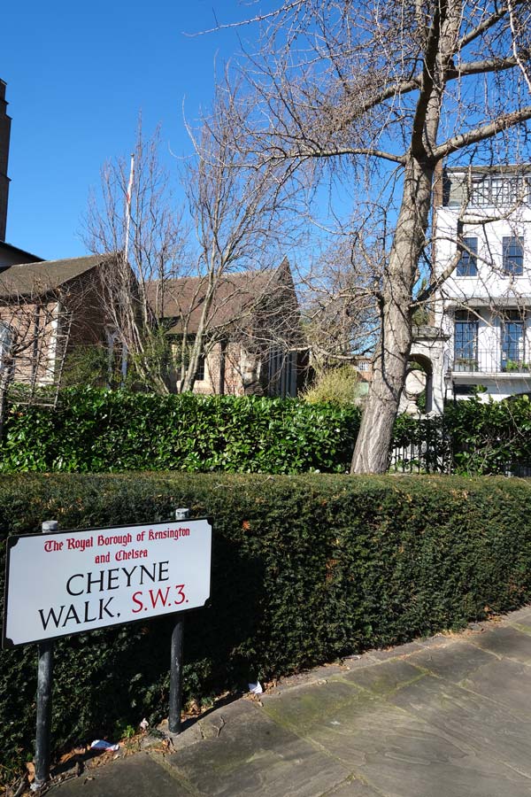 street sign saying cheyne walk in front of hedge and tree and houses