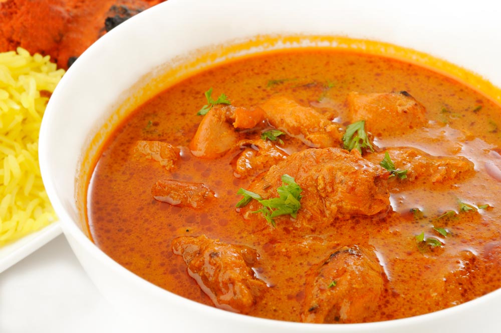 bowl of chicken tikka masala with a side of pilau rice