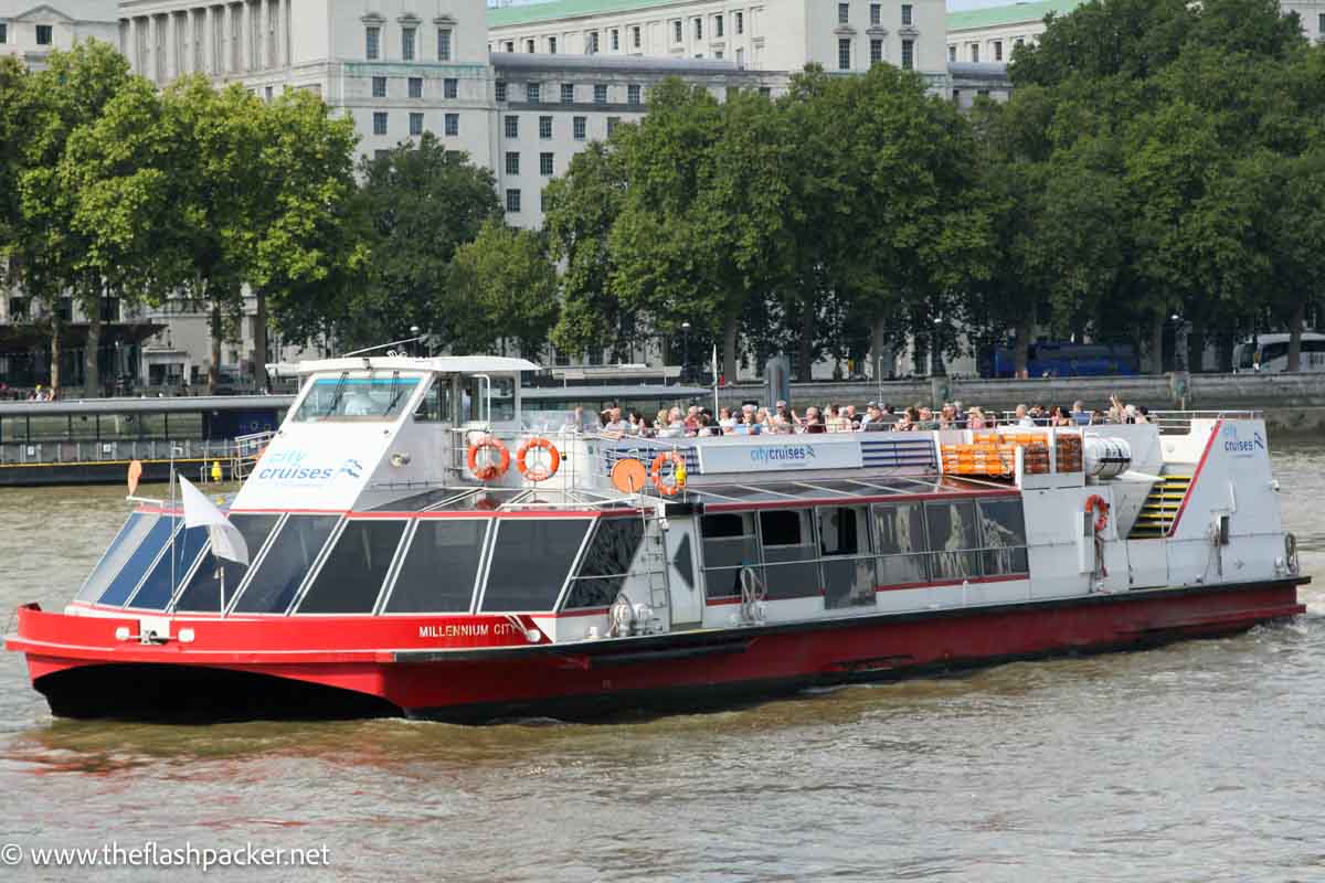 small red and white cruise boat on river thames in london