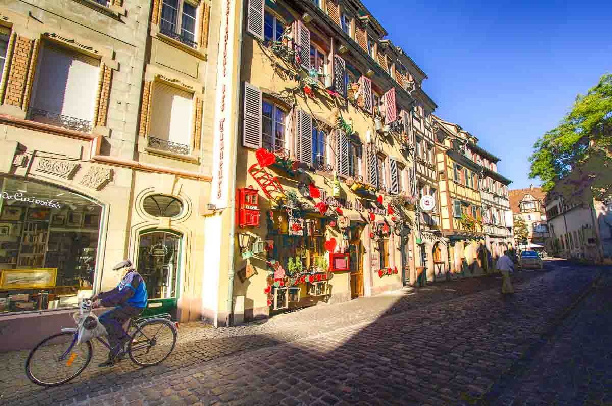 man riding bike along medieval street in colmar france