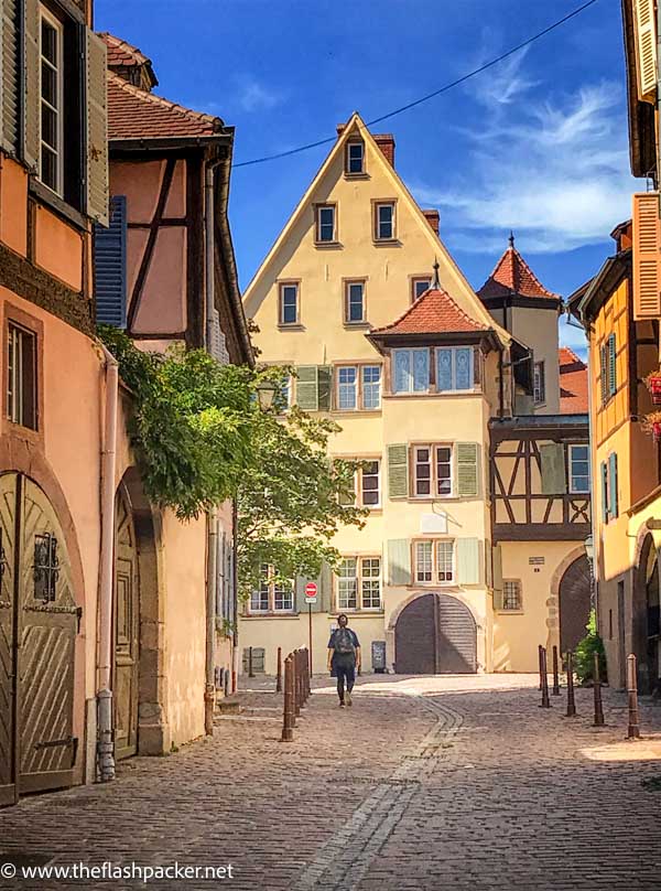 woman walking along street with gabled buildings