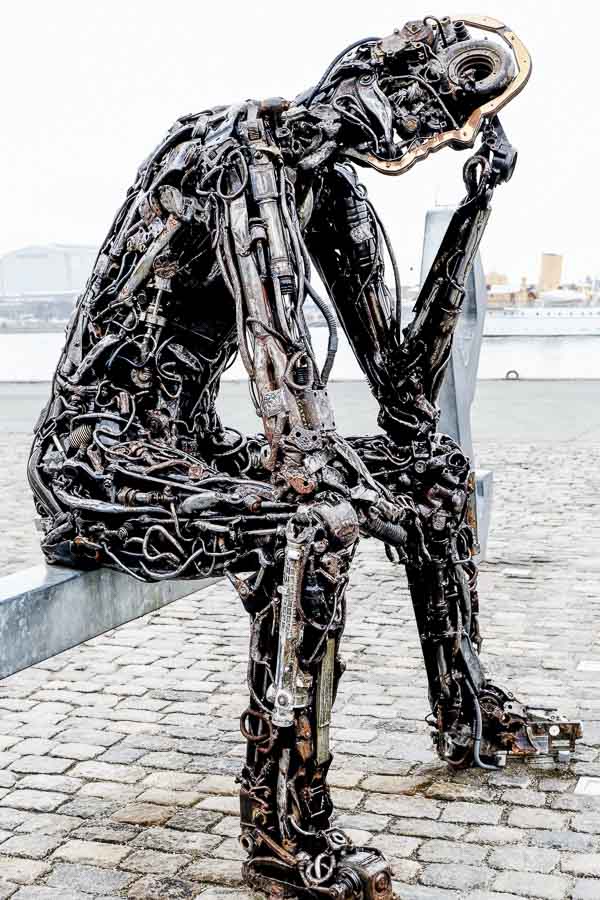 sculpture of thinking man made out of car parts