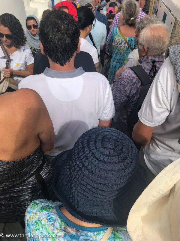 a crowd of people moving down steps in santorini greece