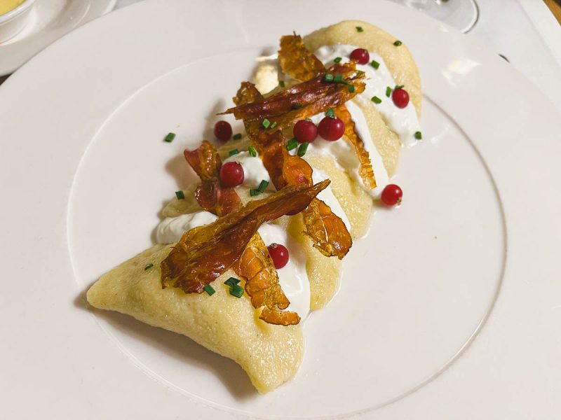 a large slovakian potato dumpling garnished with onions and red berries