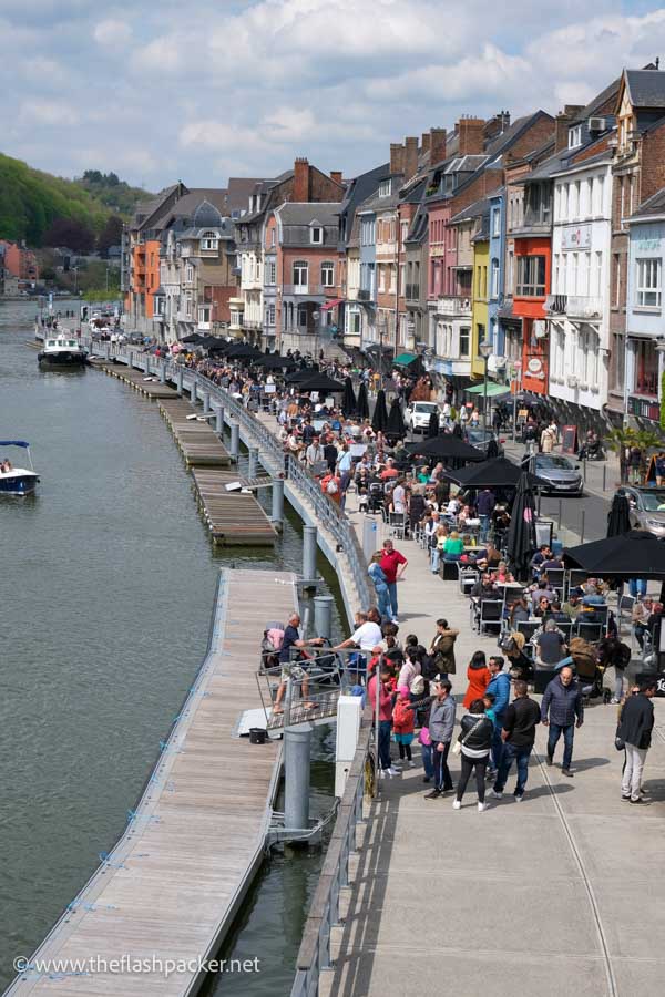 a busy riverside promenade lined with brightly coloured buildings