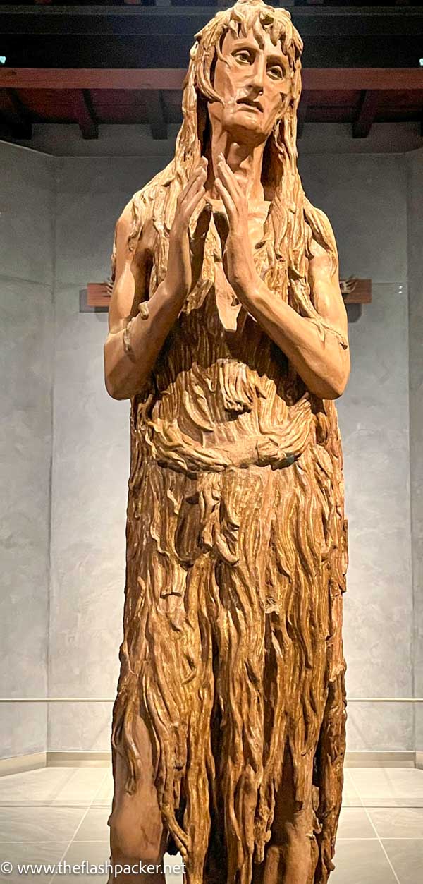 wooden sculpture of an emaciated woman in prayer