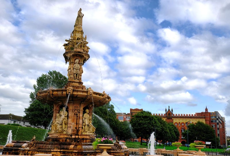 ornate fountain in a square with a red brick building