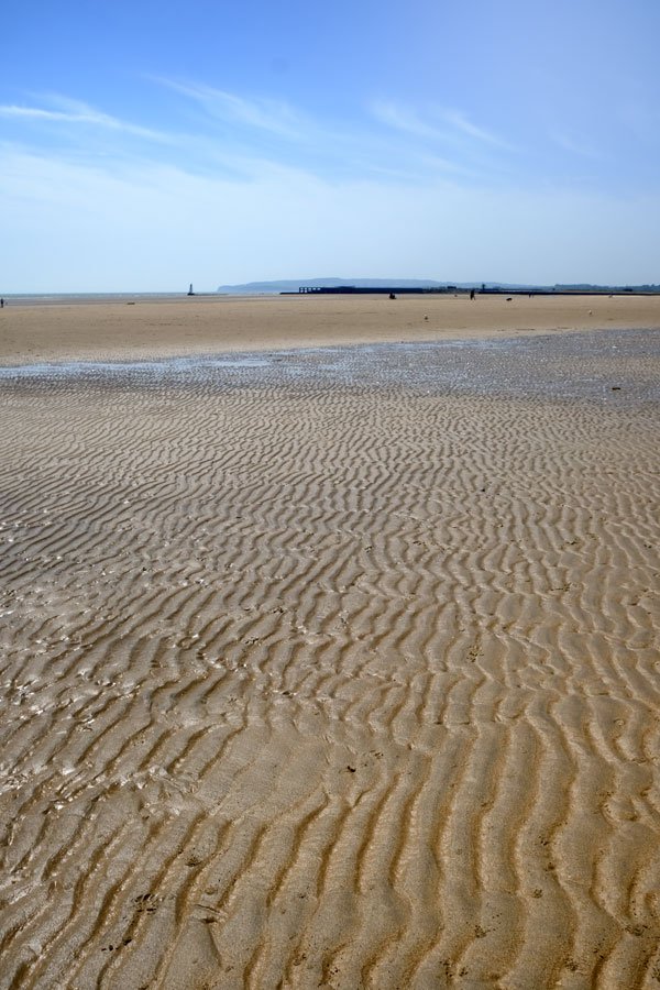 broad sand beach with ripples and tidal pools