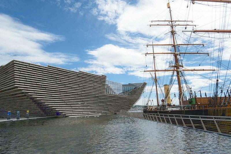 exterior of modern v and a museum in dundee next to an old ship