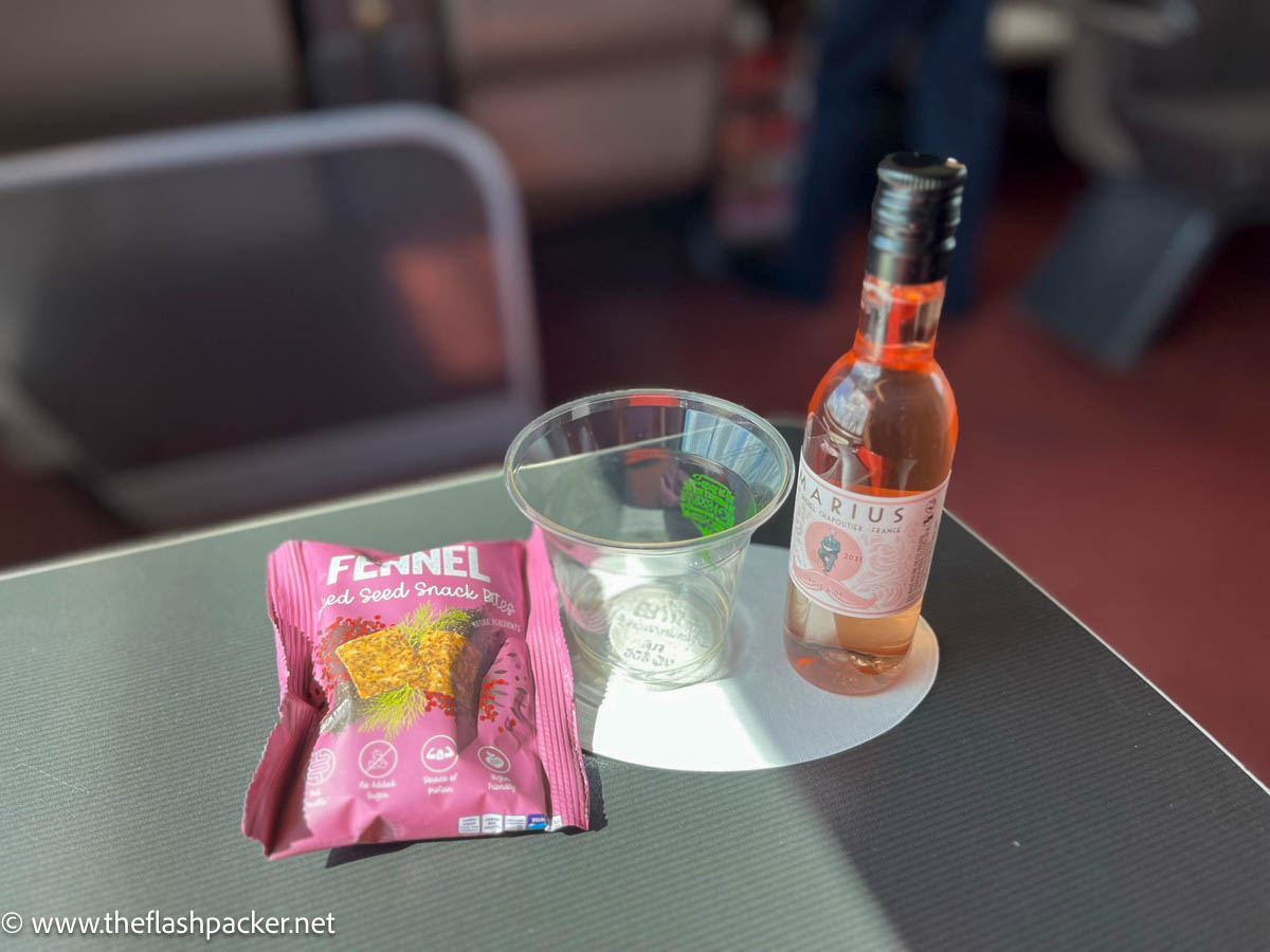 a packet of fennel crisps and a plastic glass and small bottle of rose wine