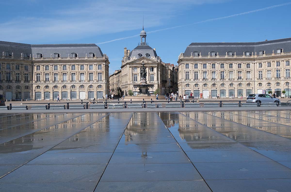 3-story elegant buildings and a square reflected in shallow water in a pavement in Bordeaux known as mirroire d'eau