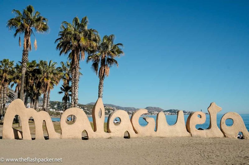 beach with palm tress and sign saying malagueta