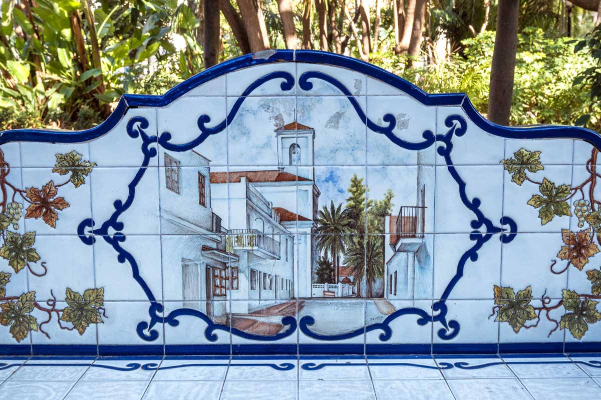 tiled bench in park showing picture of a pretty street in marbella spain