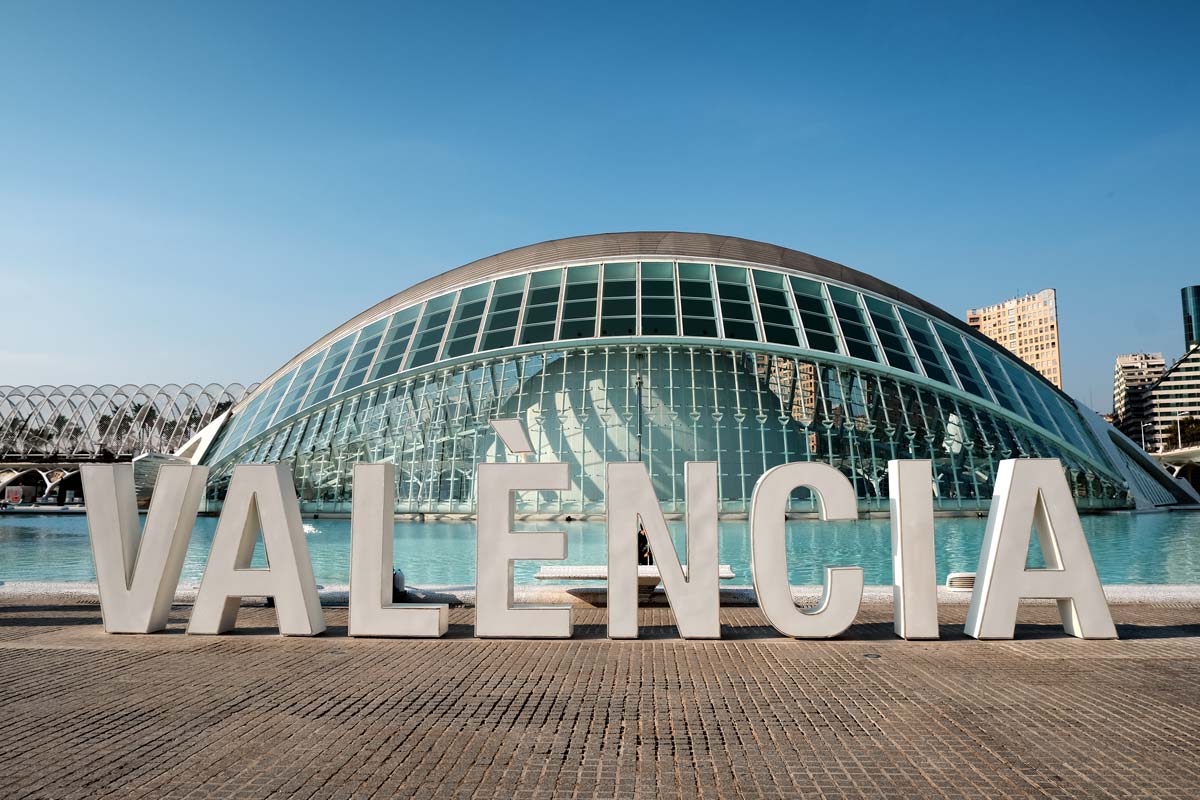 sign spelling valencia in front of lake and futuristic dome-shaped building