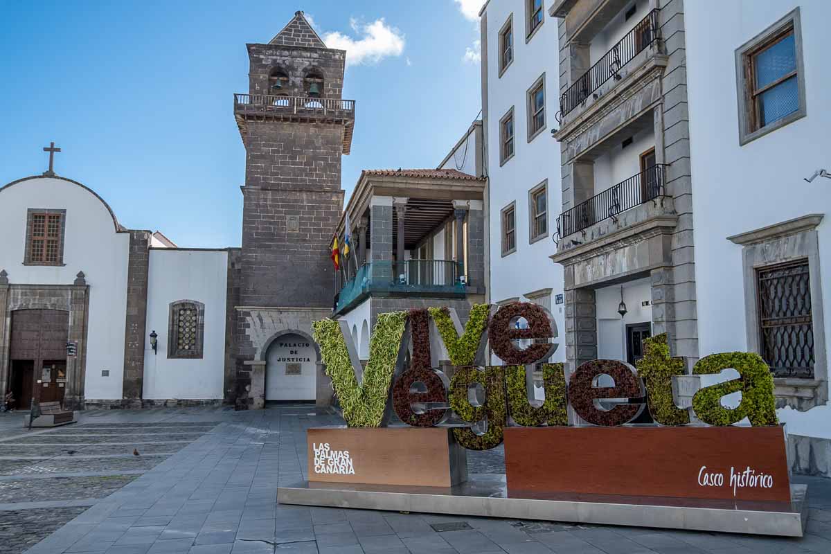 small square with a church and bell tower and a sign saying vive vegueta