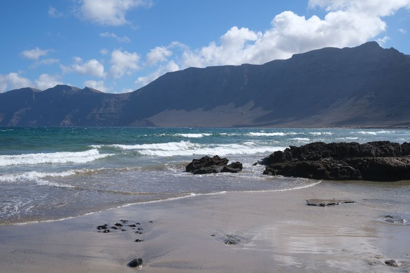 sandy beach with rock pools and cliffs in distance