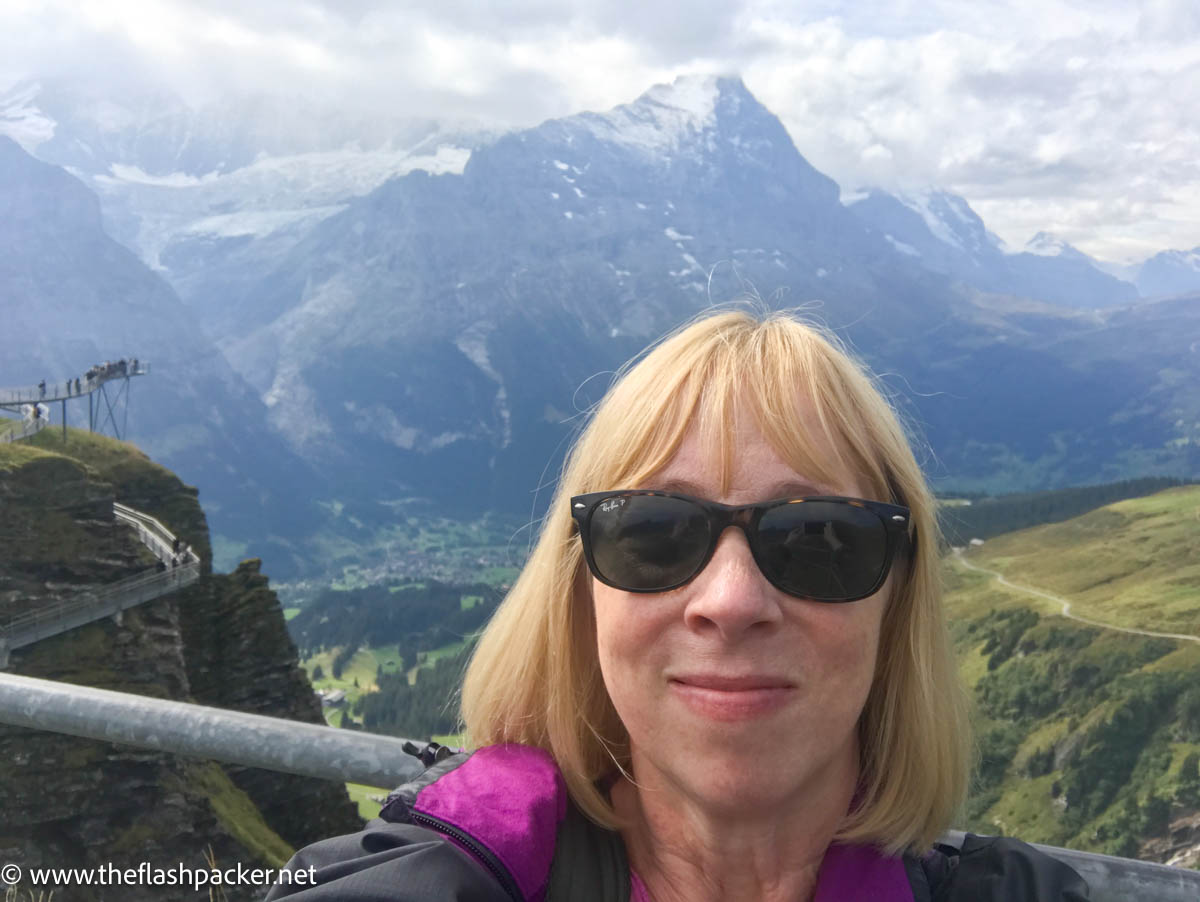 self portrait of blond woman known as the flashpacker by alpine valley in switzerland