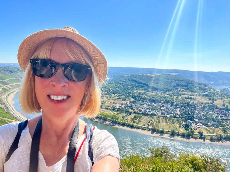 woman in sunglasses and hat in front of a rhine river view