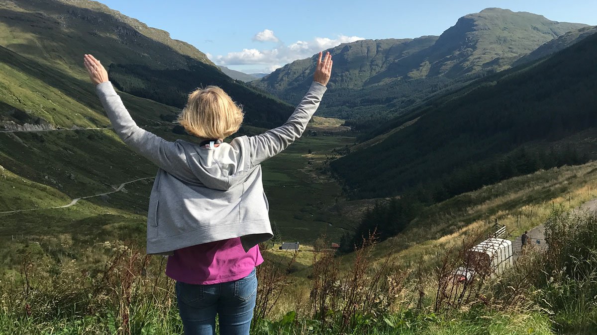 solo traveller with her arms outstretched in lush valley