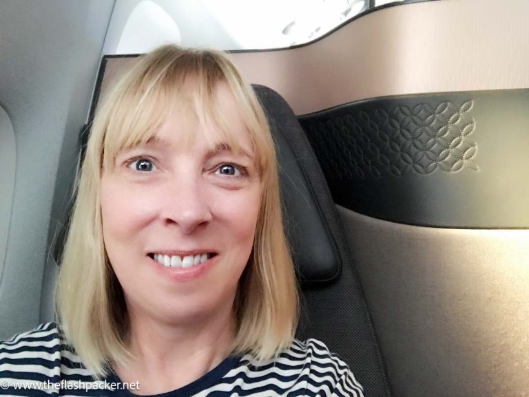 woman with blonde hair sitting in a business class seat on a plane