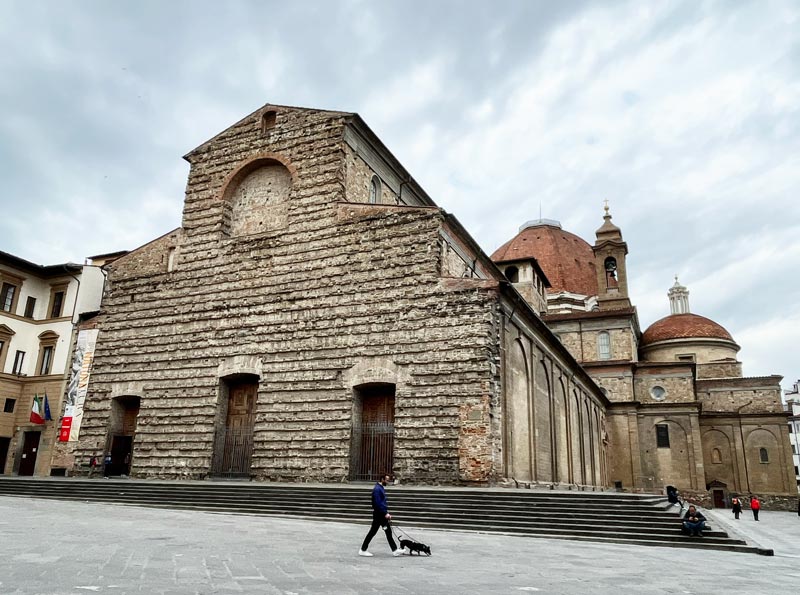 man walking a dog outside an old basilica