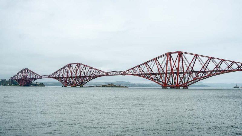 red iron cantilever bridge across wide river