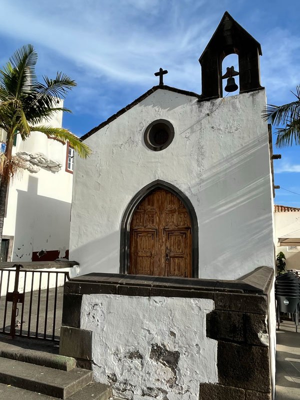 small whitewashed chapel with wooden door and bell tower